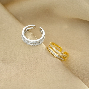 Detail of silver and gold double-layered rings with sparkling zircon on textured cloth