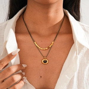 Detailed shot of double-layer gold necklace featuring hexagonal pendant and tiger eye stone
