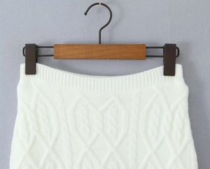 Detailed view of white cable knit texture and ribbed waistband on a slim skirt