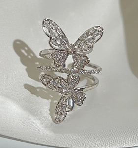 Detailed view of the double butterfly ring with sparkling zircon inlays on white satin