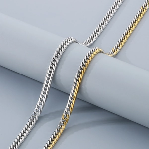 Détail de chaînes cubaines argentées et dorées bicolores sur un support gris