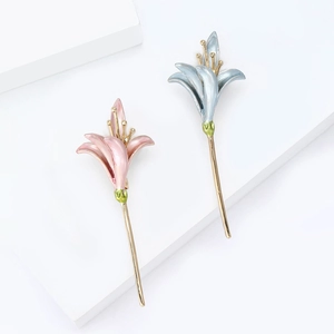 Elegant enamel narcissus flower brooches in pink and blue with gold stems on white background