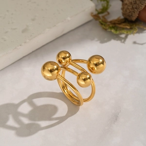 Minimalistischer offener Ring aus goldenem Edelstahl mit polierten Kugeln auf Marmor