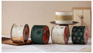 Close-up of dark green and white Christmas ribbons with gold reindeer and snowflake patterns