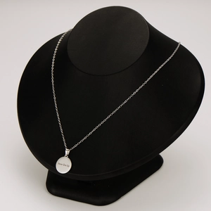 Silver stainless steel necklace with 'Never Give Up' circular pendant on mannequin