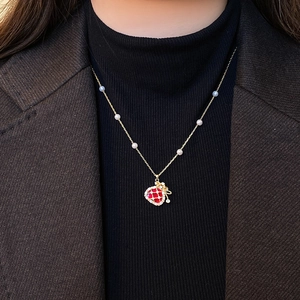 Gold plated pearl necklace with a red heart pendant and cubic zirconia bow detail