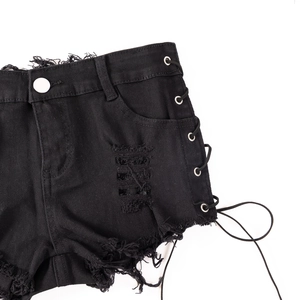 Detail der schwarzen Denim-Shorts mit seitlicher Schnürung und Fransenrand auf weißem Grund