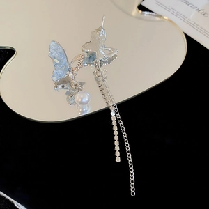 Vue détaillée de boucles d'oreilles papillon avec ailes bleu clair, perles et glands argentés