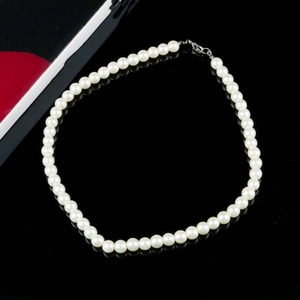 Elegant single-layer pearl necklace with silver lobster clasp on reflective black surface