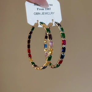 Detailed macro of gold hoop earrings with multi-color rectangular zircon stones