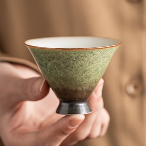 Retro kiln glazed ceramic teacup with green starlight gradient finish held by hand