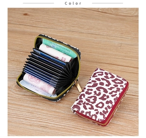 Detail of leopard print accordion card holder with gold zipper on wooden surface