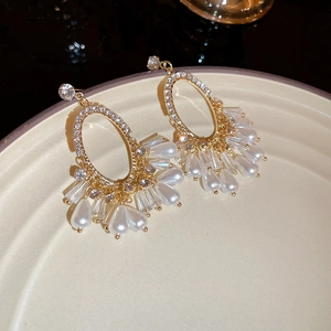 Vue macro des boucles d'oreilles dorées à glands avec cristaux et gouttes de perles blanches