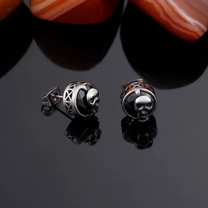 Detail of punk silver skull earrings with black beads and hollow geometric patterns