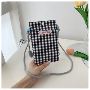 Detail of checkered crossbody phone bag featuring woven label and rope strap