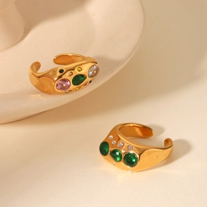 Detail of irregular hammered gold ring with inlaid colorful zircon stones on matte background