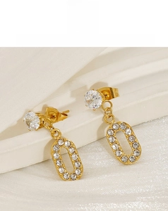 Macro shot of gold-plated crossover earrings with pavé-set zircon on white velvet