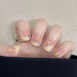 Detail of short press-on nails with cartoon stars and colorful cream drip design