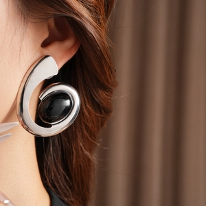 Silver-tone C-shape sculpted earring with a large black oval gemstone on a model's ear