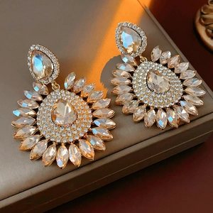 Macro shot of gold floral earrings with champagne teardrop stones and shiny rhinestones