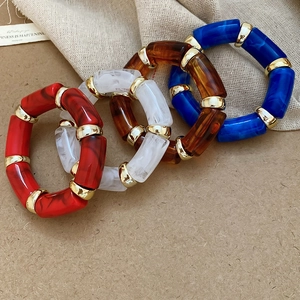 Detail of four acetate resin bangles in blue, brown, marble, and red with gold metal rings