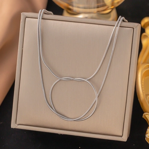 Close-up of silver snake chain necklace with elegant knot design on a jewelry box