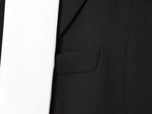 Close-up of black blazer fabric featuring contrast lapel details and breast pocket seam