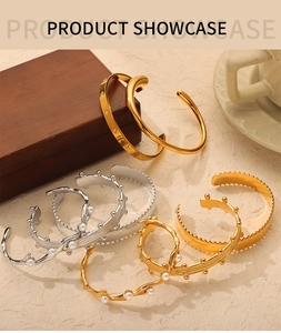 Detail shot of 18k gold and silver titanium open bangles with pearls on a wooden tray
