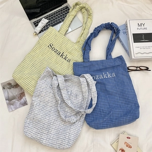 Checkered canvas tote bags in yellow, blue, and white with ruffled handles and logo print