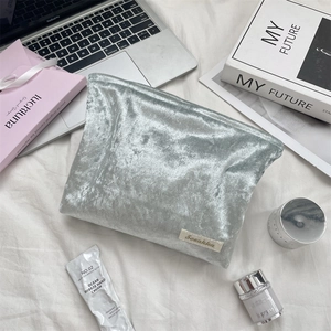 Detail showing high-quality silver velvet fabric and minimalist brand label on travel bag