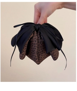 Detailed view of the leopard print fabric texture and black satin bow on the hair clip