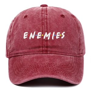 Detail of white ENEMIES embroidery and color dots on a washed burgundy baseball cap