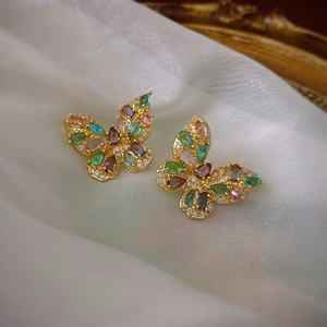 Macro shot of gold butterfly earrings inlaid with colorful zircons in a vintage luxury style
