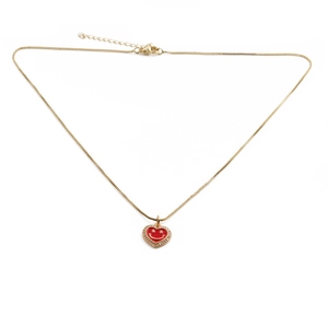 Close-up of gold plated necklace with red enamel heart pendant and sparkling crystals