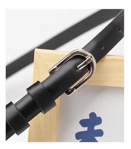 Close-up of black leather belt with silver alloy pin buckle and textured finish