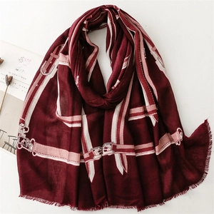 Detail of burgundy scarf with belt pattern print and fine fringe edges on a magazine