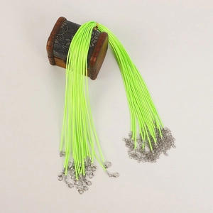 Macro shot of neon green waxed cord necklaces with silver lobster clasps on a wood box