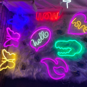 Glow of various LED neon signs including butterflies and words on soft plush background