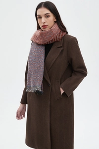 Close-up of orange and blue houndstooth scarf with tassels on a brown herringbone coat
