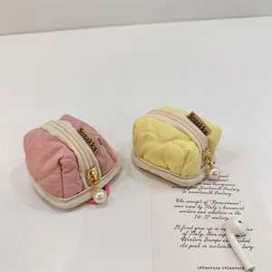 Detailed view of quilted heart AirPods pouches in pink and yellow with pearl charms
