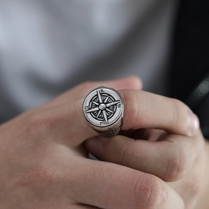 Close-up of vintage steel ring featuring an engraved compass dial on a male model hand