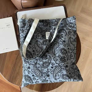 Close-up of paisley pattern on grey linen tote bag with cream-colored handles