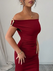 Detail of red off-shoulder dress featuring metallic gold buckle and ruching texture