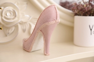 Close-up of pink high heel jewelry holder featuring fabric texture and woven trim details