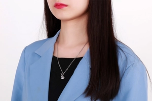 Détail du collier avec pendentif guitare argenté sur un mannequin en veste bleue