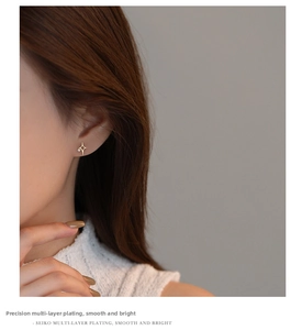 Close-up of golden polar star stud earring with zircon on ear of a model