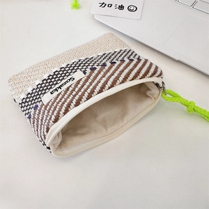 Detail of woven beige and brown striped makeup pouch with vibrant neon green zipper puller
