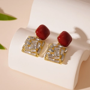 Detail of vintage burgundy acrylic stud earrings with crystals and golden square frame