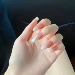 Close-up of long ballerina press-on nails with soft pink to white gradient finish