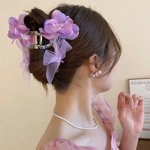 Detail der lila Haarklammer mit Organza-Blume und langem Band in der Frisur am Model